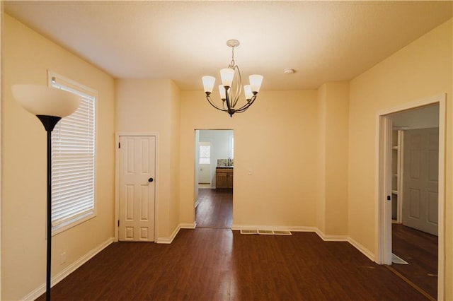 unfurnished room with dark wood-type flooring and a notable chandelier