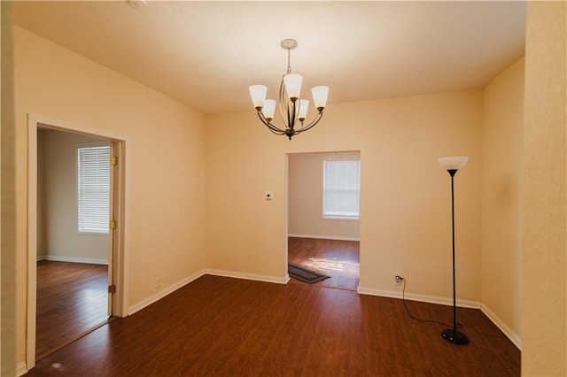 empty room featuring dark hardwood / wood-style flooring and an inviting chandelier