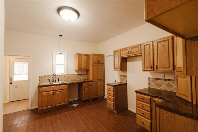 kitchen with decorative light fixtures, decorative backsplash, sink, and dark wood-type flooring