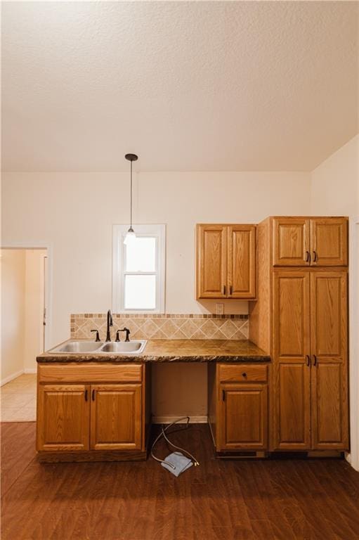 kitchen with backsplash, sink, hanging light fixtures, and dark hardwood / wood-style floors