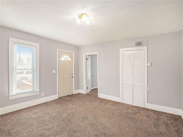 carpeted entryway featuring a textured ceiling, visible vents, and baseboards