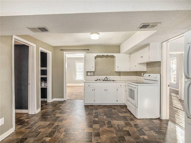 kitchen featuring visible vents, a wealth of natural light, and white range with electric stovetop