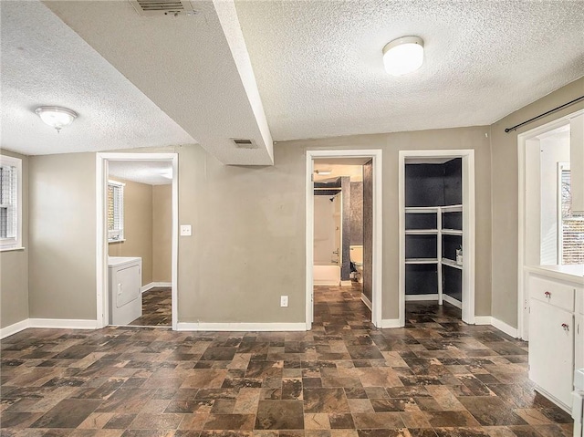 unfurnished bedroom with visible vents, ensuite bath, washer / dryer, and baseboards