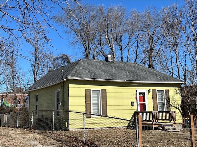 bungalow-style home featuring a shingled roof and a fenced front yard