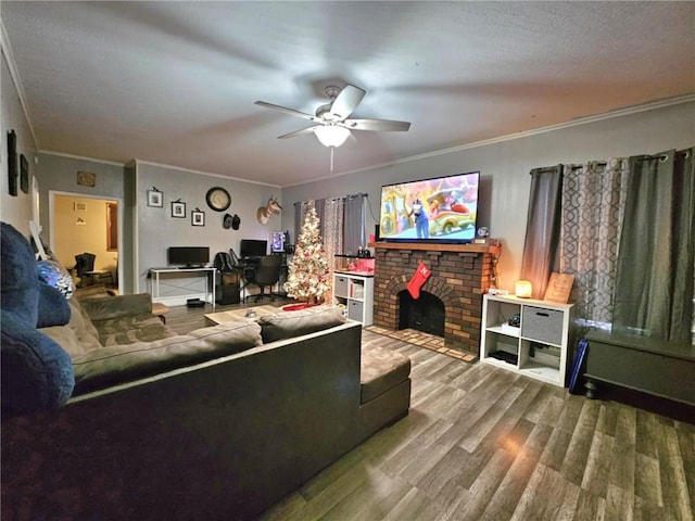 living room featuring crown molding, ceiling fan, wood-type flooring, and a fireplace