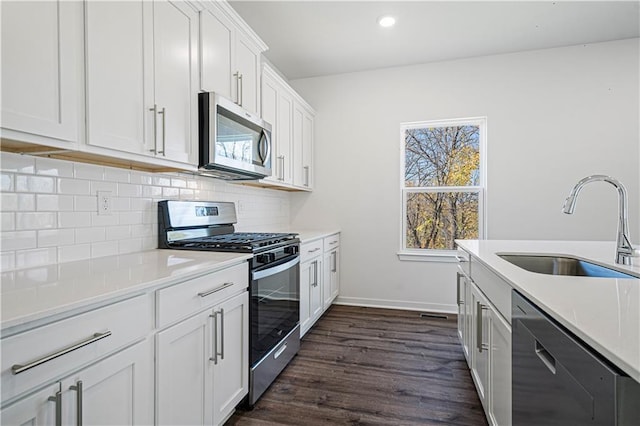 kitchen with white cabinetry, sink, dark wood-type flooring, stainless steel appliances, and tasteful backsplash