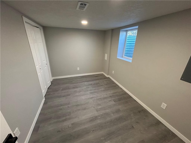 basement featuring dark hardwood / wood-style floors and a textured ceiling