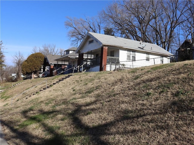 view of side of home featuring a lawn and covered porch