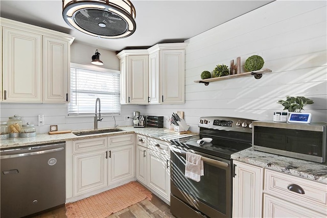 kitchen featuring light stone countertops, sink, wood walls, light hardwood / wood-style floors, and appliances with stainless steel finishes