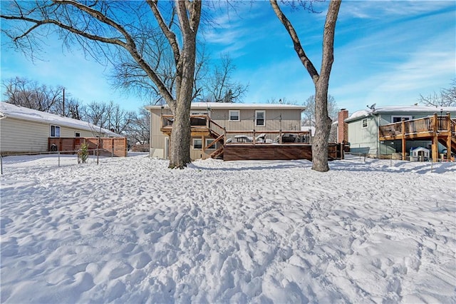 snow covered back of property with a wooden deck