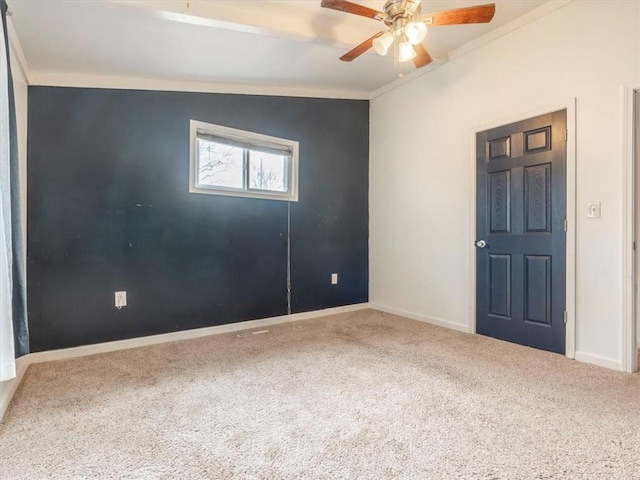 empty room with lofted ceiling, carpet floors, ceiling fan, and ornamental molding