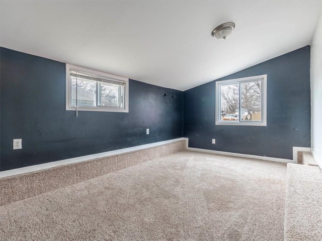 carpeted empty room featuring vaulted ceiling