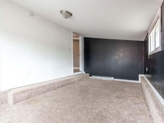 carpeted empty room featuring a baseboard heating unit