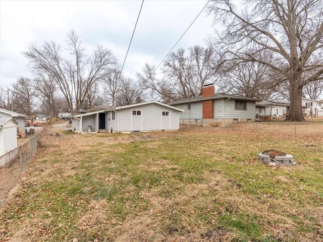 back of property with a fire pit and a lawn