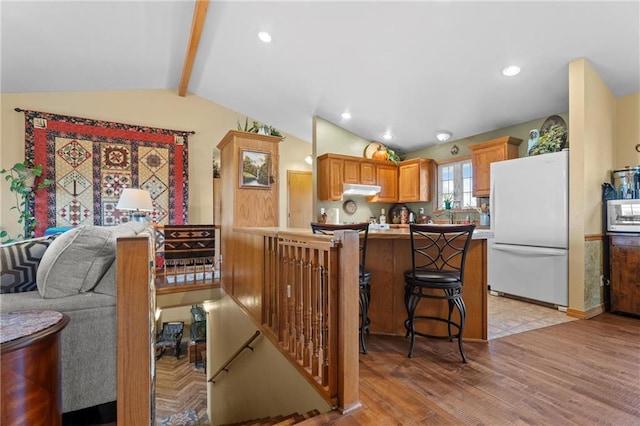 kitchen featuring a kitchen breakfast bar, lofted ceiling with beams, white refrigerator, kitchen peninsula, and light hardwood / wood-style floors