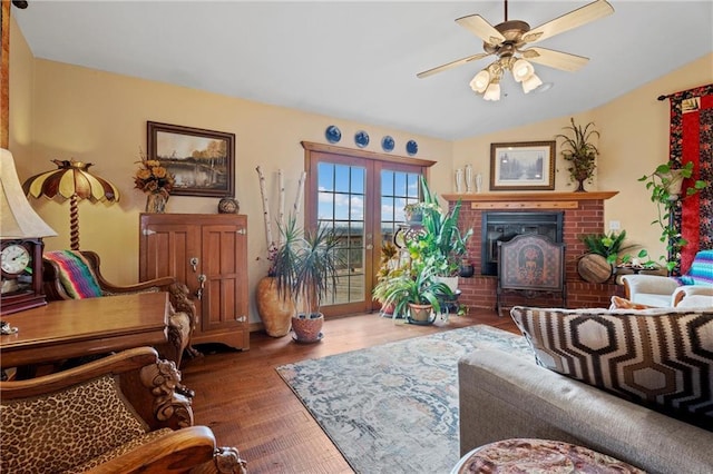 living room with french doors, vaulted ceiling, ceiling fan, hardwood / wood-style flooring, and a fireplace