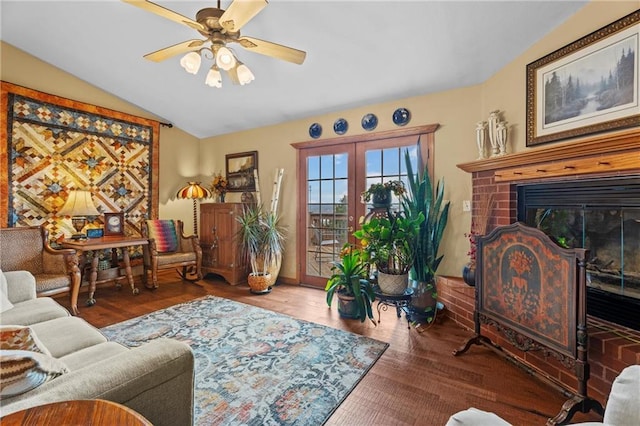 living room with ceiling fan, french doors, hardwood / wood-style floors, lofted ceiling, and a fireplace