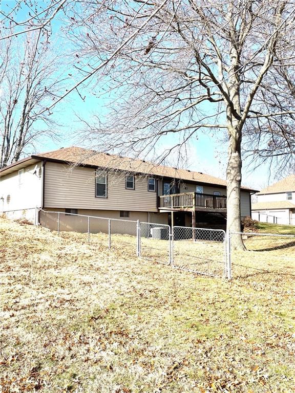 back of property with a lawn and a deck