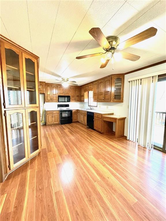 kitchen with light wood-type flooring, a textured ceiling, ceiling fan, sink, and black appliances