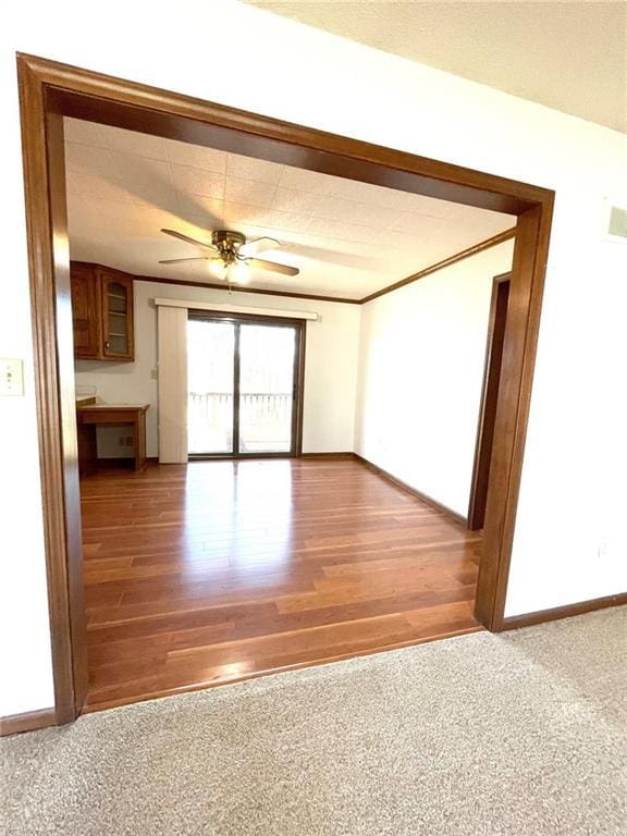 unfurnished room featuring wood-type flooring, built in desk, and ceiling fan