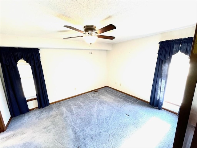 spare room featuring a textured ceiling, carpet floors, and ceiling fan