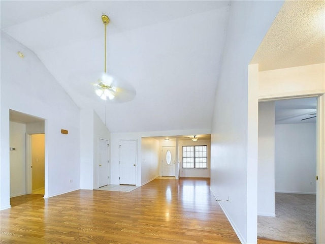 unfurnished living room featuring high vaulted ceiling, light hardwood / wood-style floors, and ceiling fan