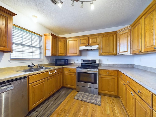 kitchen featuring stainless steel electric stove, dishwasher, sink, a textured ceiling, and light hardwood / wood-style flooring