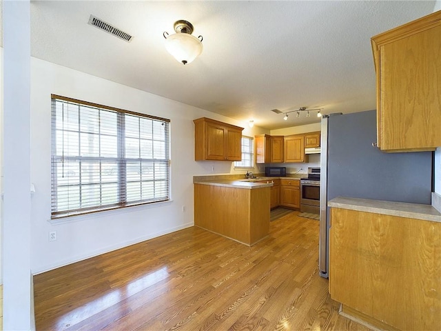 kitchen with sink, stainless steel range with electric cooktop, rail lighting, and light wood-type flooring