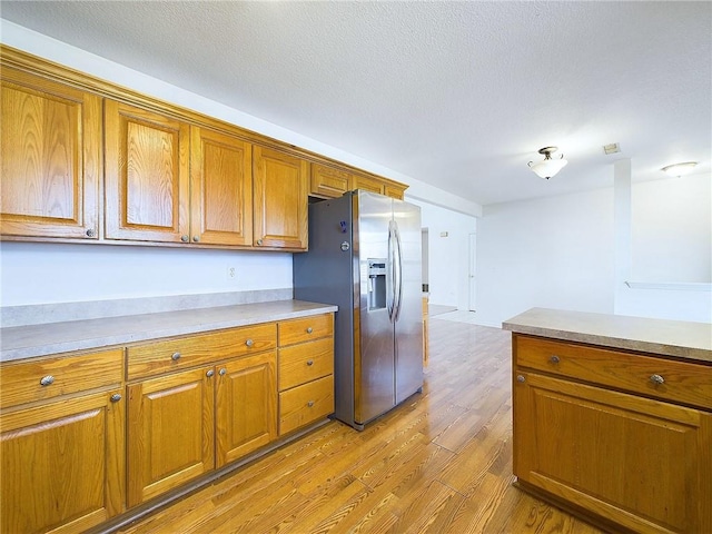 kitchen with stainless steel fridge, light hardwood / wood-style floors, and a textured ceiling