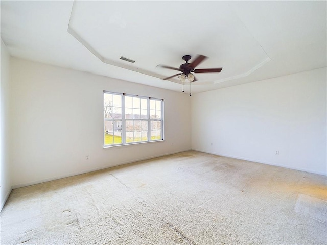 spare room featuring light carpet, a raised ceiling, and ceiling fan