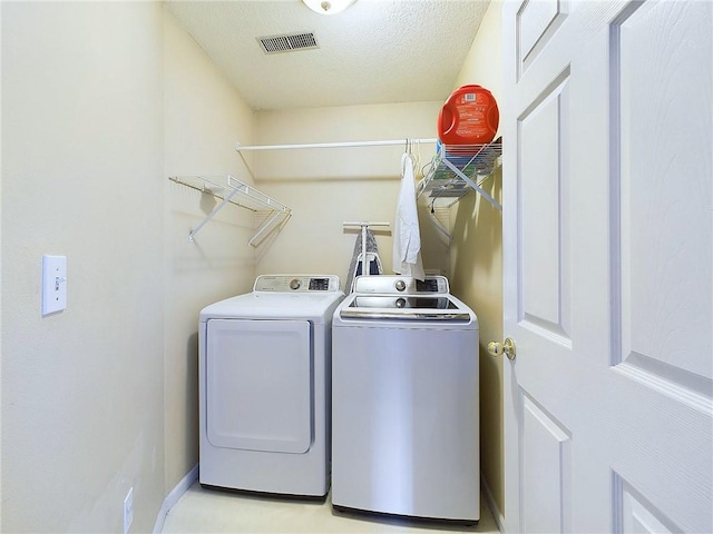 clothes washing area featuring a textured ceiling and washer and clothes dryer