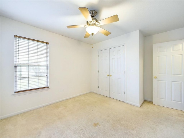 unfurnished bedroom with light colored carpet, ceiling fan, and a closet