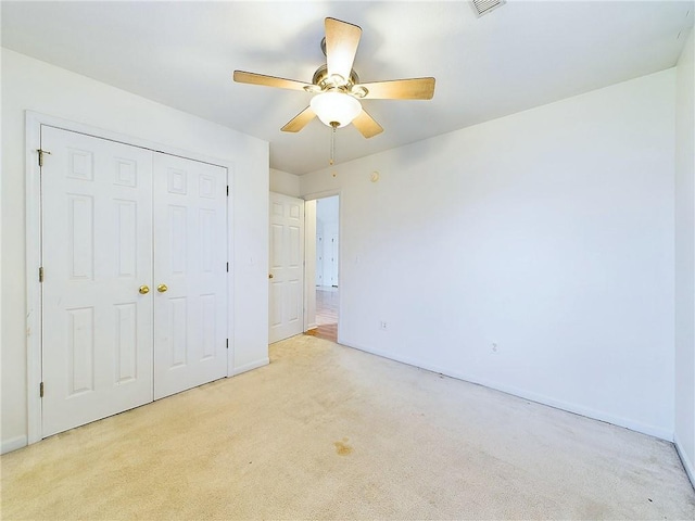 unfurnished bedroom featuring ceiling fan, light colored carpet, and a closet