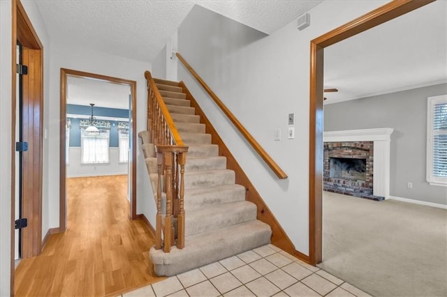 stairs featuring tile patterned flooring, a textured ceiling, and a brick fireplace