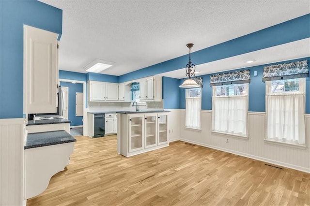 kitchen with sink, hanging light fixtures, light hardwood / wood-style floors, a textured ceiling, and white cabinets