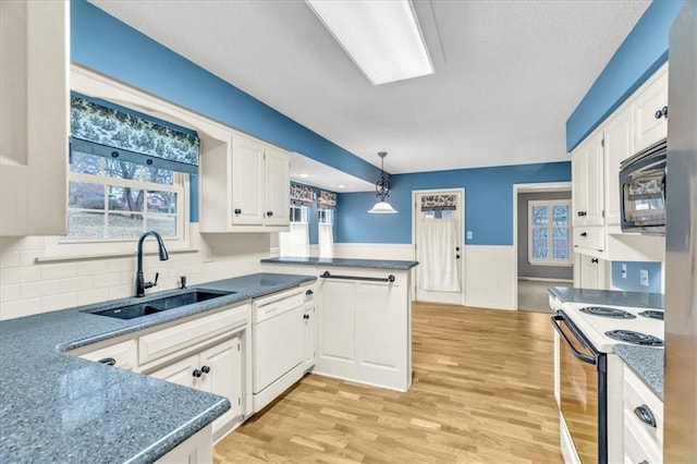 kitchen with kitchen peninsula, white appliances, sink, decorative light fixtures, and white cabinets