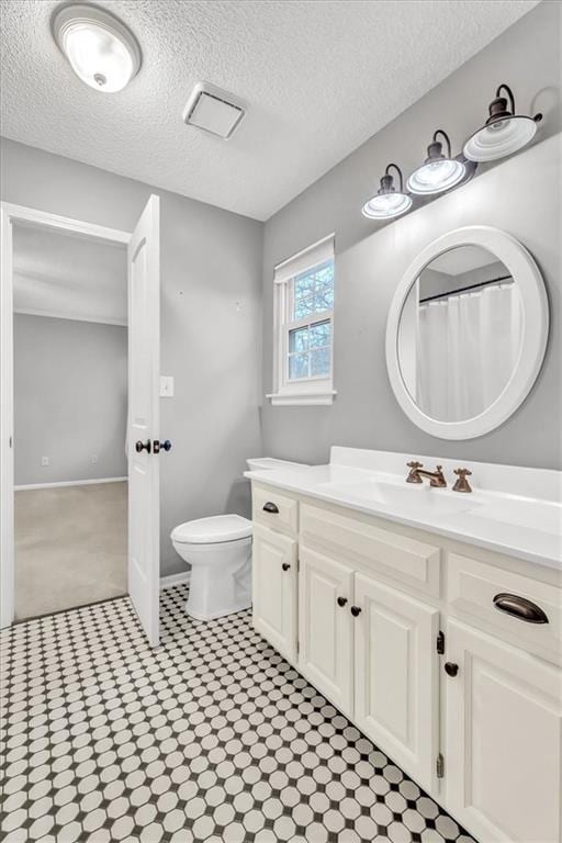 bathroom with vanity, toilet, and a textured ceiling