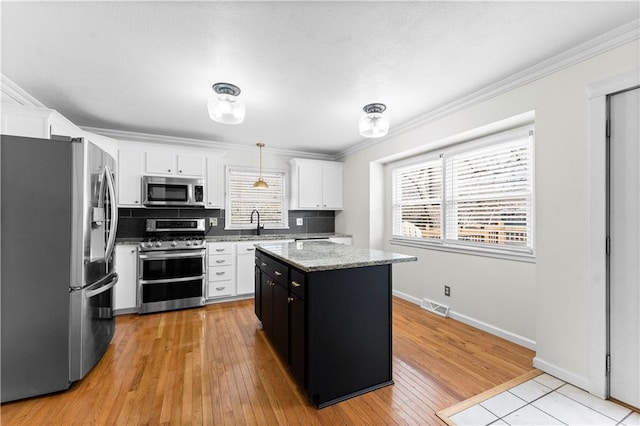 kitchen featuring backsplash, stainless steel appliances, white cabinets, a center island, and hanging light fixtures