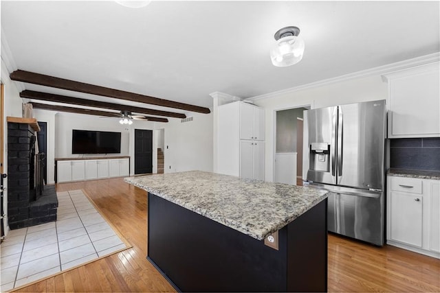 kitchen featuring a center island, ceiling fan, stainless steel fridge, beam ceiling, and white cabinetry