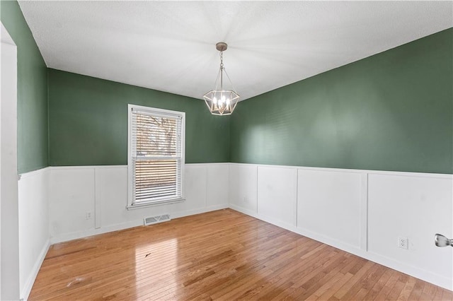 empty room with light hardwood / wood-style flooring and a notable chandelier