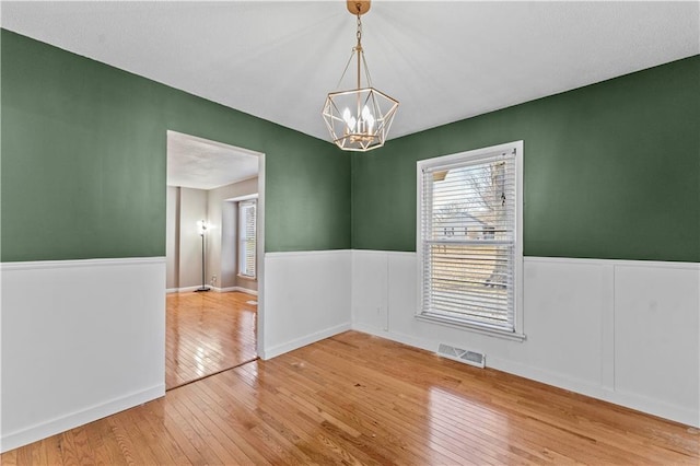 empty room featuring light hardwood / wood-style floors and an inviting chandelier