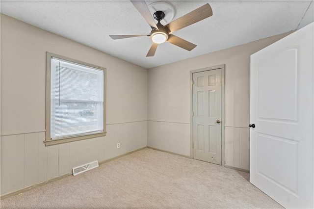 carpeted empty room with a textured ceiling and ceiling fan