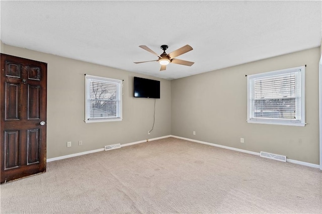 spare room featuring plenty of natural light, ceiling fan, and light carpet