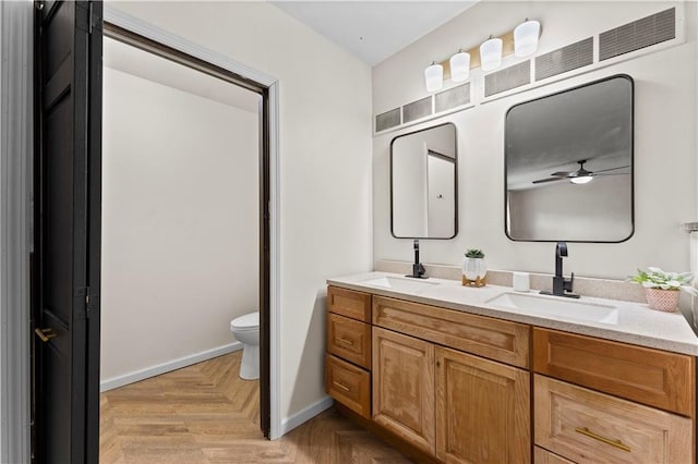 bathroom with vanity, parquet flooring, ceiling fan, and toilet