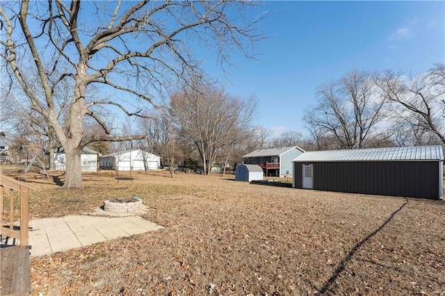 view of yard featuring an outdoor structure and an outdoor fire pit