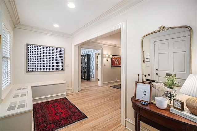 corridor featuring light hardwood / wood-style floors, crown molding, and plenty of natural light