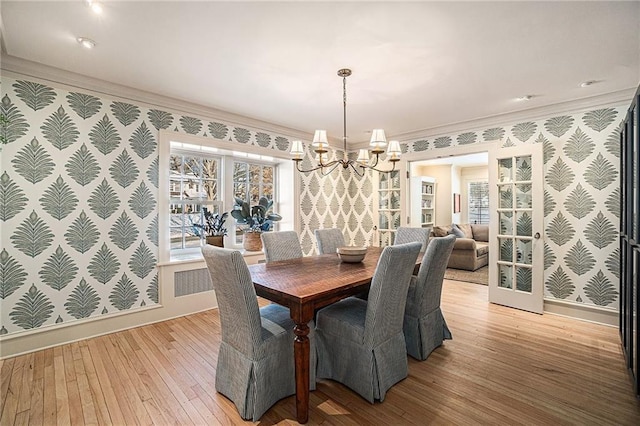 dining area featuring ornamental molding, a notable chandelier, and light hardwood / wood-style flooring