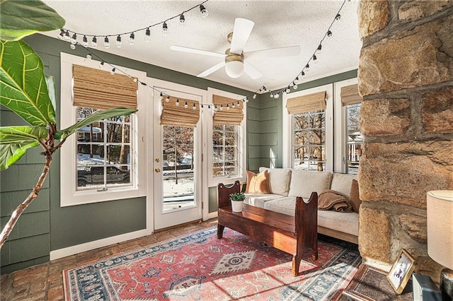 living area with a textured ceiling, ceiling fan, and plenty of natural light