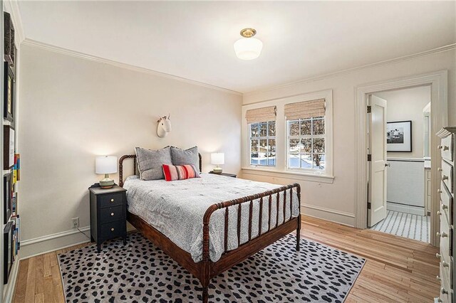 bedroom featuring ensuite bathroom, light hardwood / wood-style floors, and crown molding