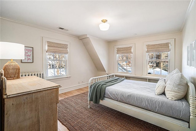 bedroom with radiator heating unit, crown molding, and wood-type flooring